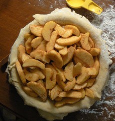 raw pie crust in pan with sliced apples filling, no top crust, Apple slices