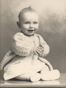 portrait, baby in sweater, baby shoes, smiling clasping hands